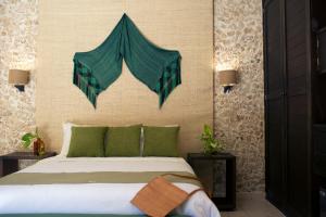 Ya'ax Hotel Boutique في ميريدا: غرفة نوم بسرير ومخدات خضراء
