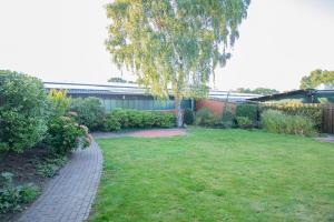 a garden with a tree and a brick walkway at Haus Hagelshoek in Bad Bentheim