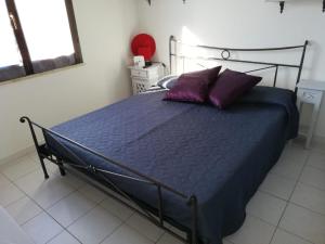 Una cama con sábanas y almohadas moradas en un dormitorio. en Ca da Ste, en Calasetta