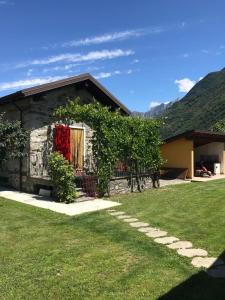 a house with a red door and a green yard at La casetta di Biancaneve Valtellina e lago di Como in Dubino