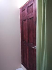 a bathroom with a wooden door next to a toilet at Belis in Alajuela City