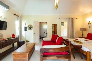 a living room with a red couch and a bed at Oceane L'union Villa in La Digue