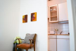 eine Küche mit weißen Schränken und einem Stuhl in der Unterkunft Ideal 2BR - Lovely for Longstays in Wien