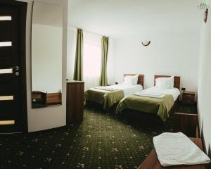 a hotel room with two beds and a mirror at Pensiunea 3 Brazi Zarnesti in Zărneşti