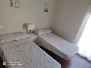 two twin beds in a small room with a window at Vivienda en El Centro de Guejar Sierra in Güéjar-Sierra