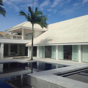 a building with a palm tree next to a swimming pool at Bougainville I Peruíbe in Peruíbe