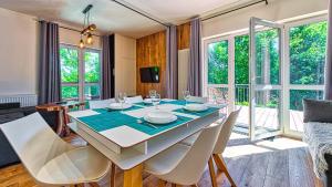 un comedor con mesa y sillas y una habitación con ventanas en Apartament Garden z Sauną Holiday Mountain Residence - 5D Apartamenty, en Świeradów-Zdrój