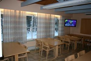 a dining room with tables and a tv on a wall at Lohijärven Eräkeskus in Lohijärvi