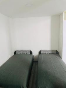 two beds in a bedroom with green sheets at Belvárosi Apartman 1 in Miskolc