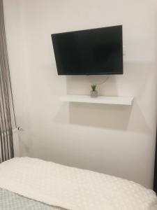 a bedroom with a tv on a white wall at Belvárosi Apartman 1 in Miskolc