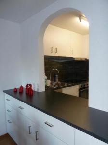 une cuisine avec des placards blancs et un comptoir noir dans l'établissement Eldorado 44, à Loèche-les-Bains