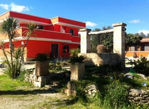a red house with palm trees in front of it at Agriturismo La Crianza in Squinzano