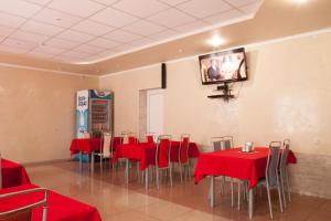 a dining room with red tables and a tv on the wall at Solar in Kropyvnytskyi