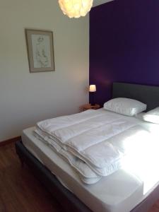 un letto bianco in una camera da letto con parete viola di La Masquénada 85 m2, neuve, moderne, confort avec grand garage a Cublac