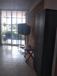Una sala de estar con un televisor de pantalla plana y una mesa. en La Casa del Volcan, en Tlayacapan