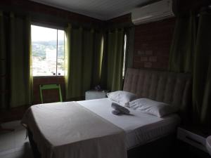 a bedroom with a white bed with a window at Pousada Monte Serrat in Bonito