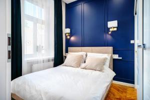 1 dormitorio con paredes azules y 1 cama con almohadas blancas en APARTAMENTY ARTE LUBLIN Niecała 11 parking free, en Lublin