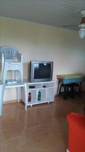 un soggiorno con TV, sedia e tavolo di Aluguel Casa em Praia Seca a Rio de Janeiro