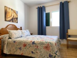 een slaapkamer met een bed met blauwe gordijnen en een raam bij Lanzarote - El Golfo in El Golfo
