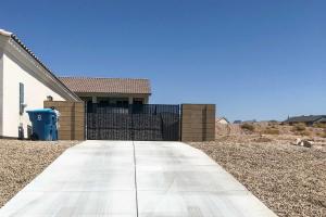 a driveway leading to a house with a fence at Luxe Home with OHV Access, 5 Mi to Lake Mohave! in Bullhead City