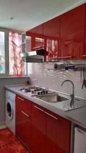 una cocina con armarios rojos y fregadero en Magic Napoli Red, en Nápoles