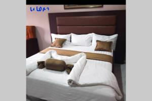 um quarto com 2 camas com lençóis brancos e almofadas em ULOM 1condos apartment em Owerri