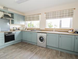 a kitchen with blue cabinets and a washer and dryer at 2 Whiterow in Powfoot