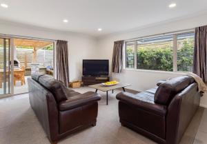 a living room with two leather chairs and a television at Rise and Shine - Taupo in Taupo