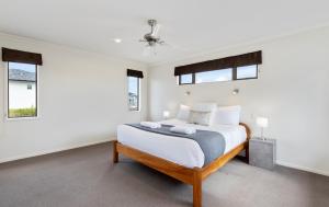 a white bedroom with a bed and two windows at Rise and Shine - Taupo in Taupo
