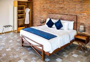 1 dormitorio con 1 cama grande y pared de ladrillo en OJO AZUL RESORT en Valle de Guadalupe