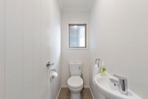 a white bathroom with a toilet and a sink at Rise and Shine - Taupo in Taupo +17 photos