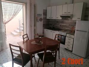 una cucina con tavolo, sedie e frigorifero di Two Hearts and a Flat San Gregorio a Leuca