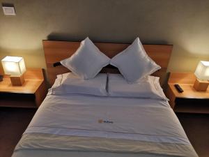 莫約班巴的住宿－Murano Hotel，一张带白色枕头的床和两张台灯