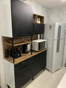 a kitchen with a counter with a microwave and a refrigerator at Apartamento Pé na Areia - Santos in Santos