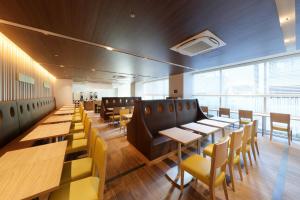 東京にある京王プレッソイン浜松町の木製テーブルと黄色い椅子が備わるレストラン
