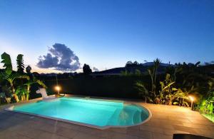 a swimming pool in a backyard at night at Villa Ohana in Sainte-Anne