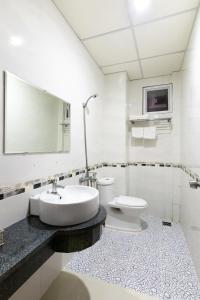 a white bathroom with a sink and a toilet at Golden Hotel in Vung Tau