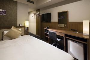 um quarto de hotel com uma cama e uma secretária com uma televisão em KOKO HOTEL Ginza-1chome em Tóquio