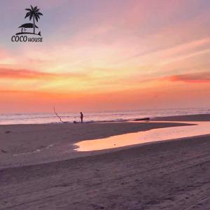 a person standing on the beach at sunset at Coco House - Playa La Barra in Buenaventura +3 photos