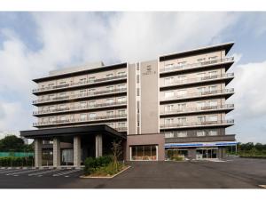 un grand bâtiment avec un parking en face de celui-ci dans l'établissement Hotel Torifito Kashiwanoha, à Kashiwa