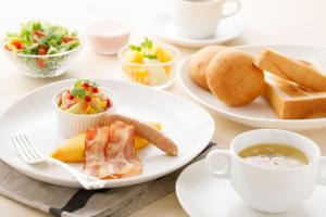 una mesa con platos de comida y tazas de café en ANA Holiday Inn Kanazawa Sky, an IHG Hotel, en Kanazawa