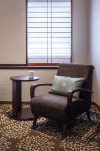 a living room with a chair and a table at ANA Holiday Inn Kanazawa Sky by IHG in Kanazawa