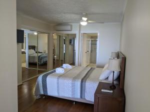 a bedroom with a bed with a lamp and a mirror at Moorings Beach Resort in Caloundra