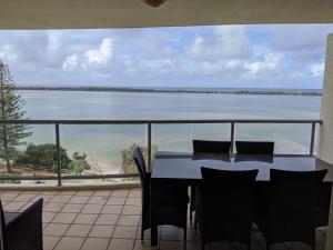a dining room table with chairs and a window at Moorings Beach Resort in Caloundra