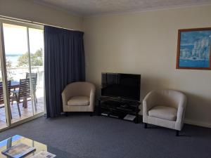 a living room with two chairs and a flat screen tv at Moorings Beach Resort in Caloundra