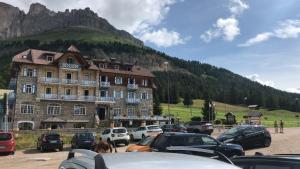a large building with cars parked in a parking lot at SUITE25 GOLFHOTEL in Carezza al Lago