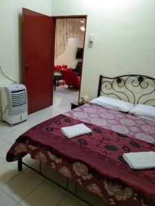 een slaapkamer met een bed met een rood dekbed bij KERAI GUEST HOUSE TEMERLOH in Kampong Telok Mengkuang