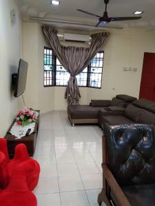 een woonkamer met 2 banken en een tv bij KERAI GUEST HOUSE TEMERLOH in Kampong Telok Mengkuang