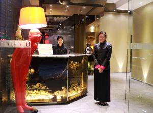 twee vrouwen die voor een toonbank staan met een standbeeld van een man bij Lan Kwai Fong Hotel - Kau U Fong in Hong Kong