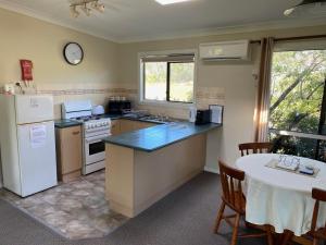 a kitchen with a table and a refrigerator at Twin Trees Country Cottages in Pokolbin